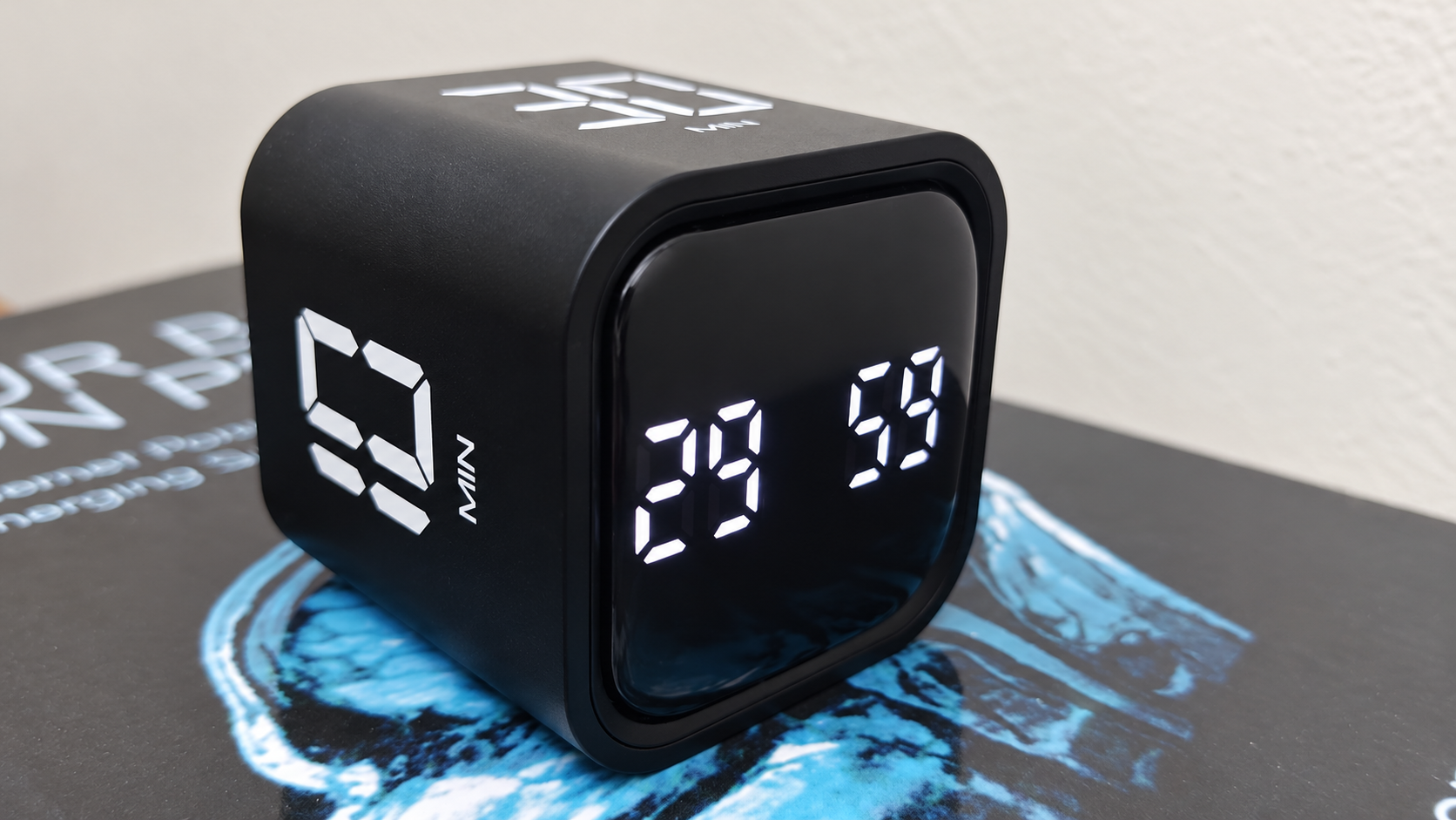 A matte black timer cube sitting on a desk showing 29:59 on a bright digital screen